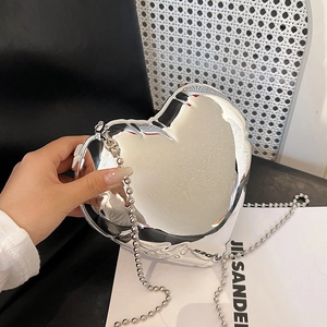 Detail of a heart-shaped silver mirror crossbody bag with metal bead chain handle
