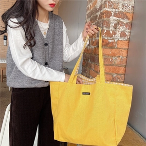 Detail of yellow canvas tote bag with checkered lining and black merciparis label