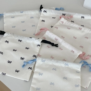 White drawstring storage bag with colorful bow prints for travel and daily organization