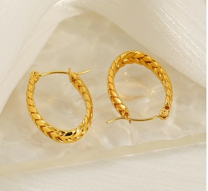 Detailed close-up of golden hoop earrings featuring a woven rope texture and pin closure