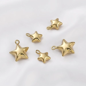 Close-up of 14K gold filled star charms in various sizes on a white silk background