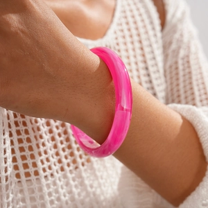 Gros plan d'un bracelet en résine magenta avec texture nuageuse au poignet