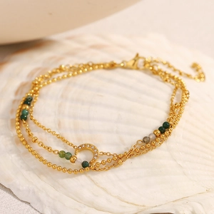 Detail view of triple-layered 18K gold-plated moon charm bracelet on a white shell