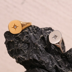 Detailed shot of 18K gold and silver North Star signet rings on a dark textured rock