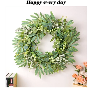 Detail of faux eucalyptus wreath with green leaves and cream berries on light background