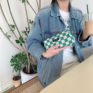 Close-up of a green checkered corduroy pencil case held by a person in a cafe