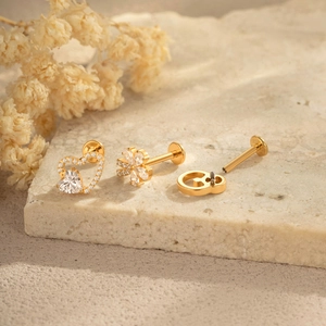 Titanium flower and heart shaped stud earrings set with zircon stones on stone surface