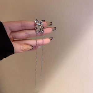 Détail de boucles d'oreilles fleurs argentées avec de longs glands en chaîne métallique