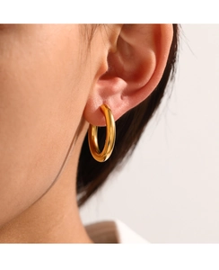 Close-up of chunky gold hoop earrings with a smooth polished finish on a female model