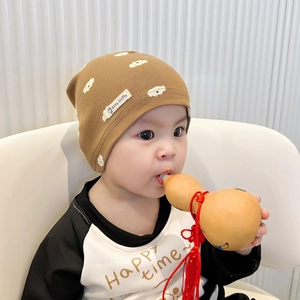 Close-up of brown cotton baby beanie with white cloud print and soft knit texture