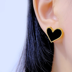 Minimalist heart earrings in black and 18K gold plating worn on a female model
