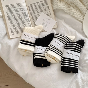 Detail of four pairs of wool socks in black and white stripes on a cozy background