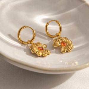 Detalle de pendientes de aro bañados en oro 18K con circón naranja y pétalos texturizados