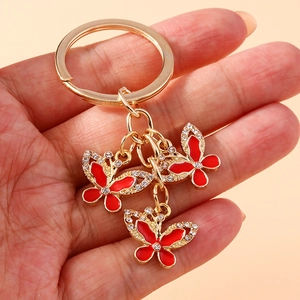 Detail of red rhinestone butterfly pendants on a gold keychain held in hand