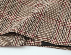 Detail of premium houndstooth fabric in brown red and beige with visible woven texture