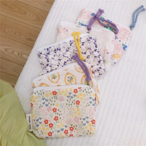 Macro detail of various floral cotton pouches with zipper closures and colorful cords