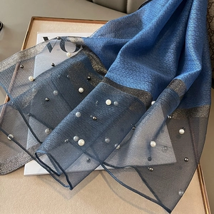 Detail of navy sheer scarf with white pearls and metallic trim on a fashion magazine