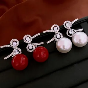 Elegant bow-shaped zirconia and pearl earrings in classic red and white colors
