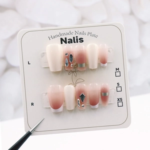 Detail of pink gradient press-on nails with silver lines and rhinestones on card