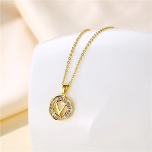 Macro shot of 18K gold letter V round pendant necklace with bagette cubic zirconia