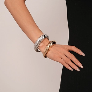 Détail de bracelets manchettes torsadés en or et argent portés au poignet d'un mannequin