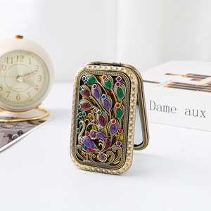Detail of vintage bronze peacock mirror with colorful enamel and inlaid rhinestones