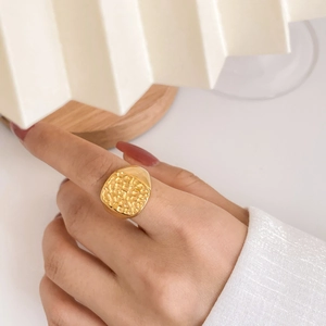 Macro shot of wide gold ring with irregular relief lunar texture on finger