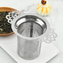 Detailed shot of stainless steel tea strainer with handles resting on a ceramic tray