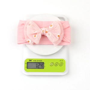 Pink daisy mesh headband with a large bow showing a weight of 12.4g on a digital scale