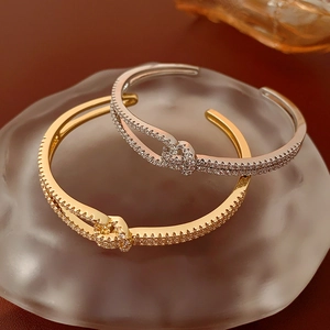 Macro detail of gold and silver double-layered zirconia bangles with twisted knot design