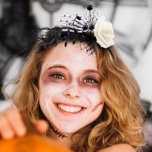 Gothic Halloween headband with white roses, black mesh, and skeleton hands on a model