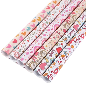 Rolls of colorful gift wrapping paper with hand-drawn LOVE and kiss prints
