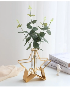 Close-up of a star-shaped gold metal vase with 'Love' text and a glass test tube insert