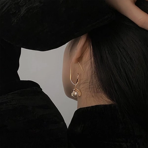 Minimalist gold geometric line earrings with pearl pendants shown on a model