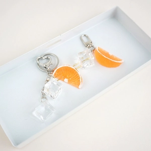 Detailed close-up of cute simulation orange slice and ice cube resin keychain charms