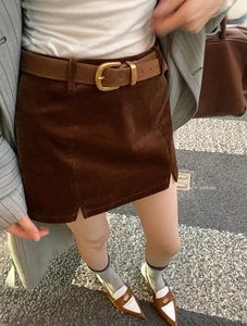 Detail of caramel corduroy mini skirt with leather belt and retro side slit design