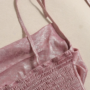 Détail macro du tissu rose métallisé avec texture élastique smockée et fines bretelles