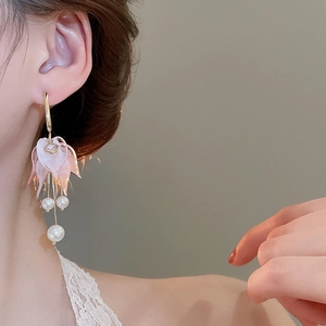 Detail of pink acrylic petal earrings with elegant pearl tassels worn by a model