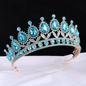 Detailed view of Baroque crown with blue teardrop crystals on white silk fabric