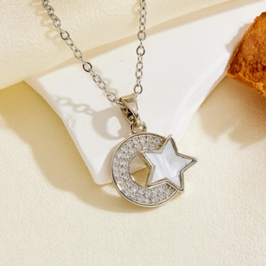 Detailed view of silver crescent moon and star pendant necklace on textured fabric