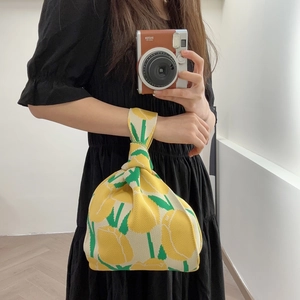 Close-up of a floral knit wrist bag with yellow tulips and green leaves pattern
