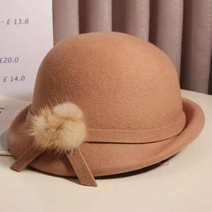 Detail of wool cloche hat featuring a plush fur pompom and elegant ribbon trim