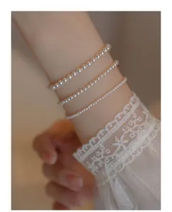 Close-up of three-layered pearl bracelets with 14k gold accents on lace sleeve