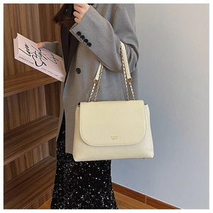 Close-up of cream PU leather handbag featuring gold chain strap and elegant flap closure