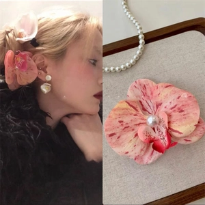 Detailed close-up of a pink orchid hair claw clip with a pearl center and matching jewelry