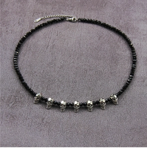 Detailed view of Gothic black crystal beaded necklace with seven silver skull pendants