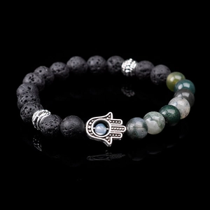 Macro shot of lava stone beads and silver Hamsa Hand charm with blue stone on a bracelet