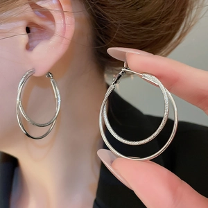 Detail shot of double-layer interlocking silver earrings with matte and polished finishes