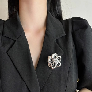 Detail of silver camellia flower brooch pinned on a black suit lapel for styling