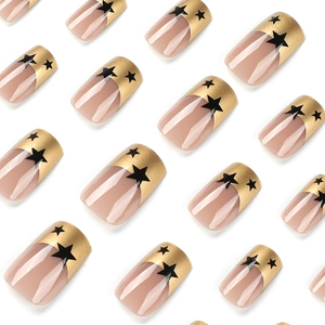 Press-on nails featuring nude base with gold French tips and black star patterns